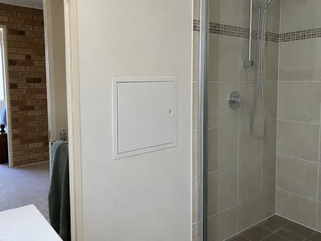 Neat access panel in a bathroom wall beside a tiled shower in Tenambit